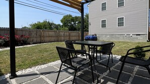 An outdoor patio with a pergola, a table, and chairs.