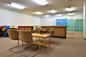 Conference room with a long table and four chairs, carpeted floor, and lockers.