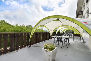 Guests can enjoy shaded seating and a lush planter on this outdoor terrace.