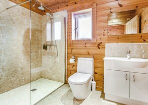 Een badkamer met een glazen douchecabine, toilet en een wastafel met houten lambrisering.