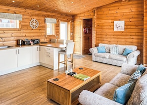 Interior de uma cabana de madeira com cozinha, sala de jantar e sala de estar.