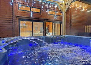 A hot tub with water jets, surrounded by wooden walls and a large window.