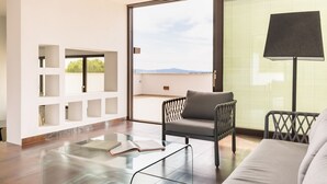 A modern living room with a glass coffee table, a grey sofa, a black armchair, and a floor lamp. There is a large window with blinds and a view of the outdoors. - GuestHost - Wonderful apartment that accommodates up to 4 people, on two levels and equipped with all comforts, including a large terrace overlooking the city and the hills. The accommodation is located in a modern condominium complex with a shared swimm (Perugia)