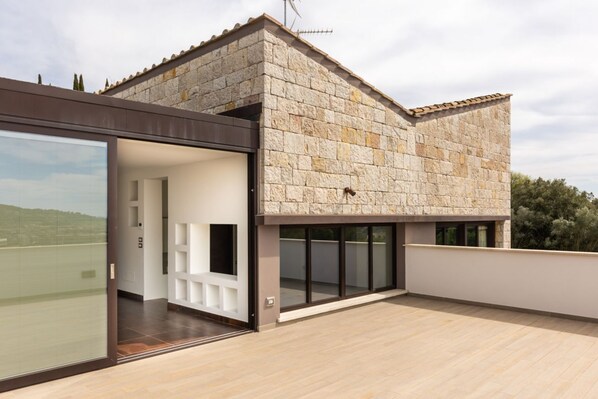 A modern house with a stone facade, large glass doors, and a flat roof.