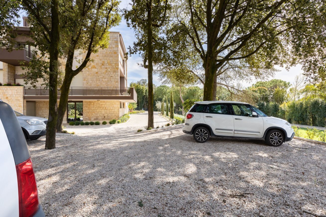Un edificio moderno con vialetto ghiaioso e auto parcheggiate.