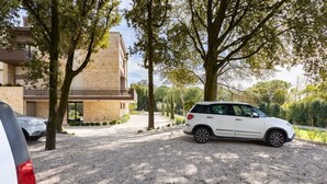 A modern building with a gravel driveway and parked cars. - GuestHost - Cozy apartment equipped with all comforts to accommodate up to 6 people, with two bedrooms and two bathrooms. The accommodation is located in a modern condominium complex with a shared swimming pool and enjoys a pleasant view of the shared ga (Perugia)