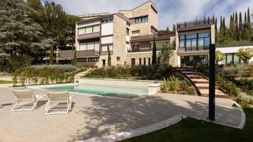 Un edificio moderno a più piani con piscina, area relax all'aperto e giardino curato.