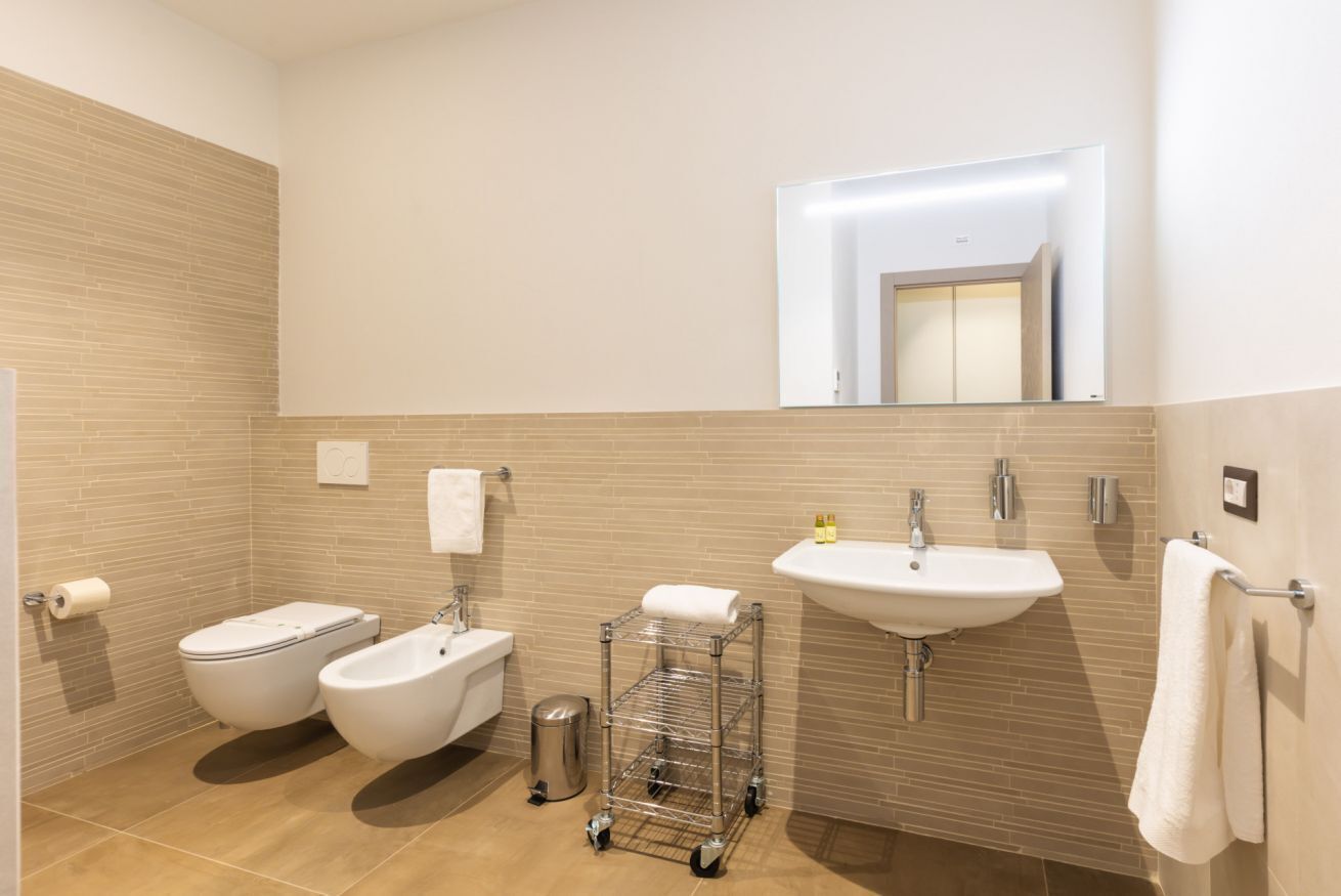 Une salle de bain moderne équipée de toilettes, d’un bidet, d’un lavabo et d’un miroir.