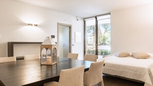 A modern room with a dining table, chairs, a bed, and a large window. - GuestHost - Cozy apartment equipped with all comforts to accommodate up to 6 people, with two bedrooms and two bathrooms. The accommodation is located in a modern condominium complex with a shared swimming pool and enjoys a pleasant view of the shared ga (Perugia)