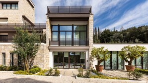 A modern two-story building with a stone facade, large windows, and a balcony.