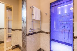 Un baño con cabina de ducha de vidrio, un perchero para toallas y suelo de baldosas.