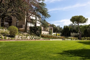 A building with a sloped roof, a large lawn, and trees in the background. - GuestHost - Elegant apartment for two people, arranged on two levels and equipped with all comforts including a balcony and shower with chromotherapy. The apartment is located in a modern condominium complex with a shared swimming pool, which enjoys a pl (Perugia)