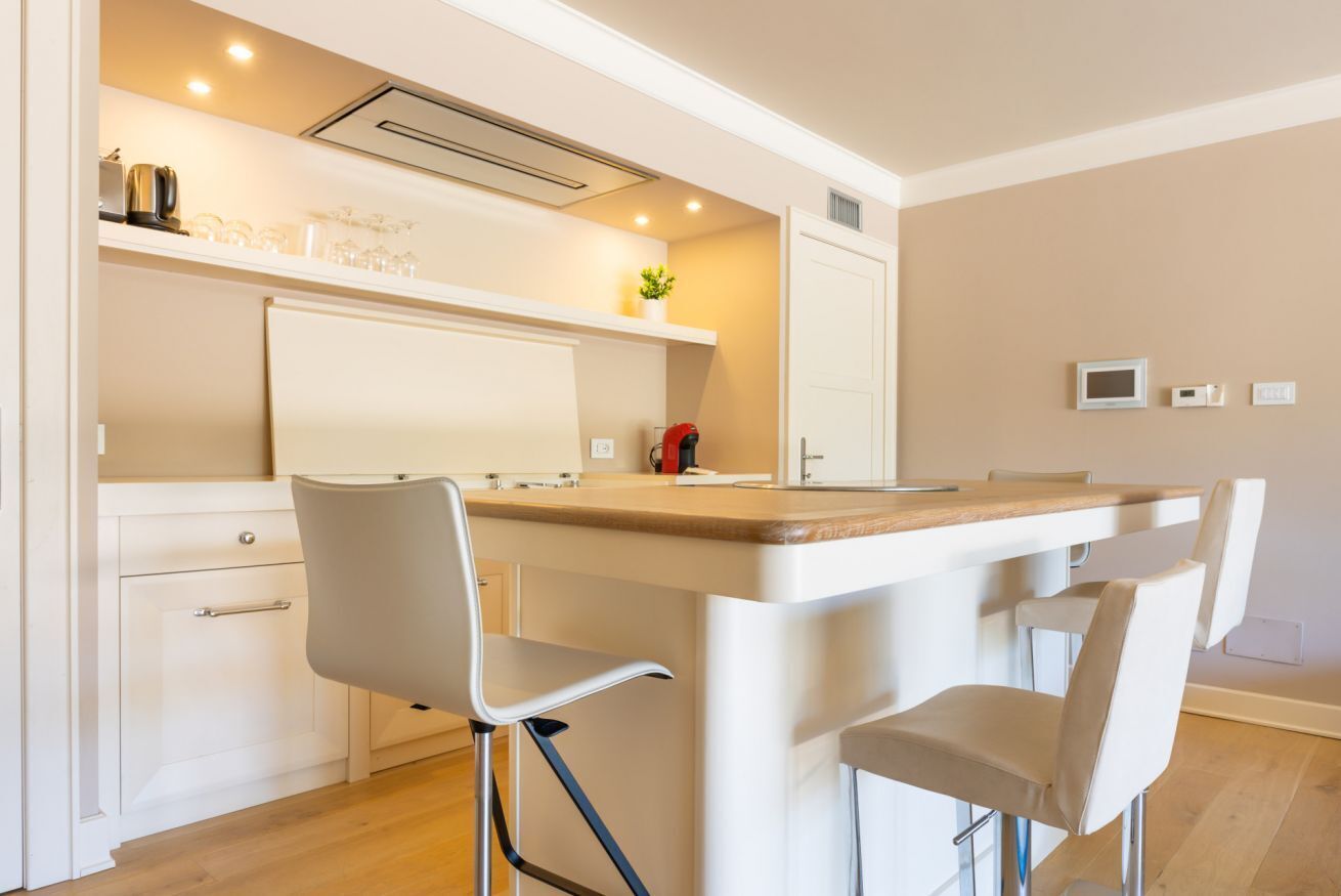 Una cocina moderna con una isla central, taburetes de bar y horno empotrado.