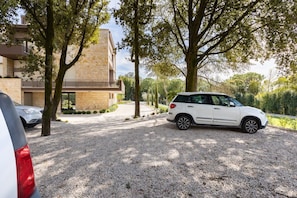 A modern building with a gravel driveway and parked cars.