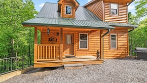 A log cabin with a porch, a grill, and a sign indicating it is a lodging facility. - Centrally Located!~Newly Built Rustic Modern Cabin!~Guest Favorite! (Sevierville)