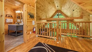 A wooden cabin interior with a bathroom, a desk, and a staircase leading to an upper level. - Centrally Located!~Newly Built Rustic Modern Cabin!~Guest Favorite! (Sevierville)