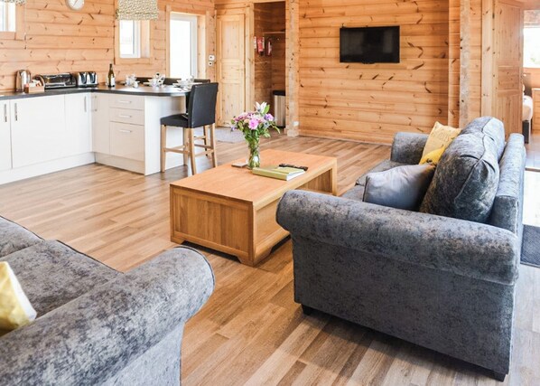 A log cabin interior with a dining area, a sofa, and a television.