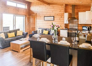 A cozy cabin interior with a dining area, kitchen, and a sofa set.