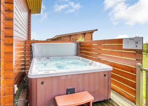 Un jacuzzi con un muelle de madera y un banco, rodeado de paredes de madera.