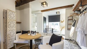 A modern bathroom with a bathtub, a round wooden table, and a seating area with a white sofa and chairs. - La chocolaterie de Roly (Philippeville)