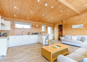 A log cabin interior with a kitchen, dining area, and living room.