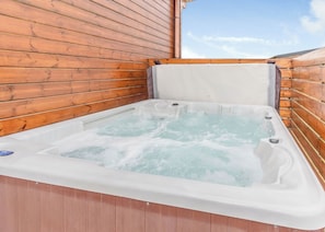 A hot tub with wooden walls and a clear sky view.