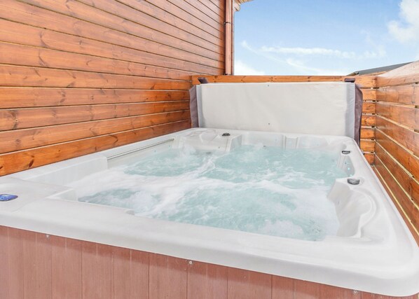 Un jacuzzi con paredes de madera y vista a un cielo despejado.