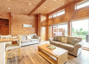 Un interior de madera con dos sofás, una mesa de centro y una zona de comedor.