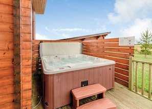A hot tub on a wooden deck with a bench, surrounded by a wooden fence and a clear sky. - Luxurious and contemporary Finnish log lodge. (Withernsea)