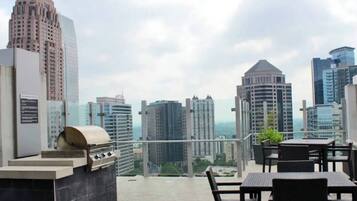 Une terrasse sur le toit équipée d’un barbecue, d’un espace salon et offrant une vue panoramique sur la ville.
