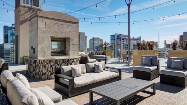Eine Dachterrasse mit Sitzgelegenheiten im Freien, einem Kamin und Blick auf die Stadt.