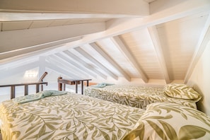 Une chambre aménagée dans les combles, avec deux lits, un bureau et une chaise.