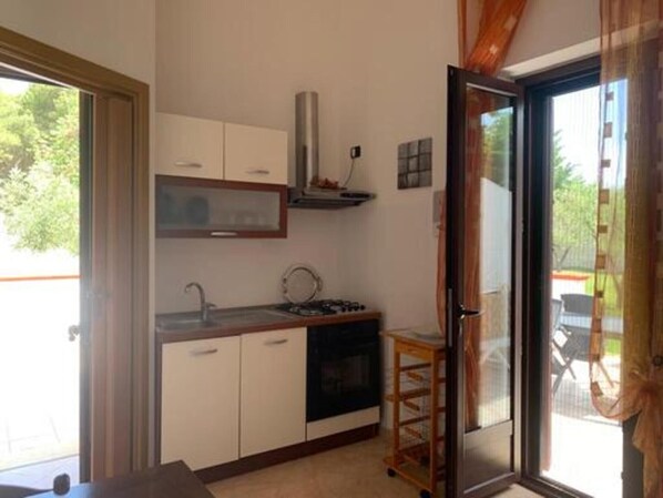 A compact kitchen with a gas stove, a sink, and cabinets.