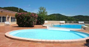 A swimming pool with a surrounding patio, a bench, and a building with a tiled roof. - Villa 'Agachelo' with Sea View, Wi-Fi and Air Conditioning (Fréjus)