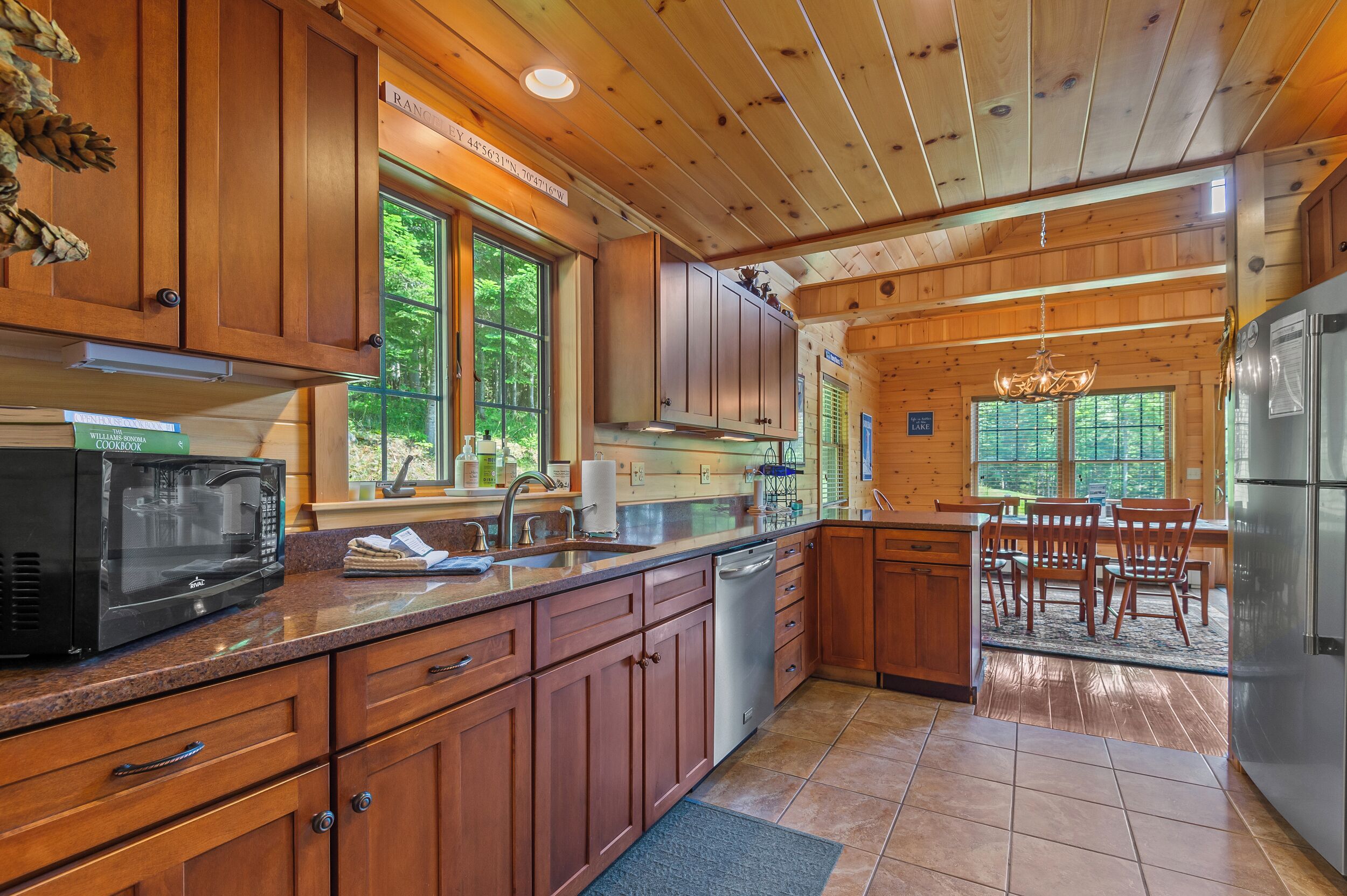 A wooden cabin kitchen with a microwave, sink, and refrigerator.