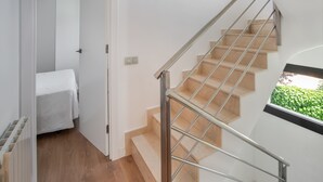 A staircase with a glass railing, a wooden floor, and a window with a green view. - Holiday Home 'Sunny House' with Sea View, Wi-Fi and Air Conditioning (Sant Pere de Ribes)