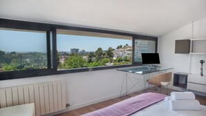 A modern hotel room with a large window, a desk, a chair, a bed, and a radiator. - Holiday Home 'Sunny House' with Sea View, Wi-Fi and Air Conditioning (Sant Pere de Ribes)