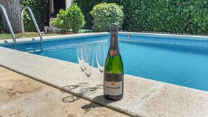 A poolside setting with a bottle of Taittinger wine and three glasses. - Holiday Home 'Sunny House' with Sea View, Wi-Fi and Air Conditioning (Sant Pere de Ribes)