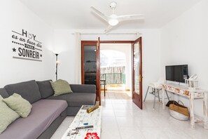 Una sala de estar con sofá, mesa de centro, televisor y ventilador de techo.