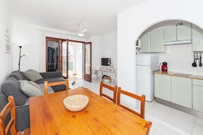 Un comedor con una mesa y sillas de madera, un sofá y una cocina con armarios y un microondas.