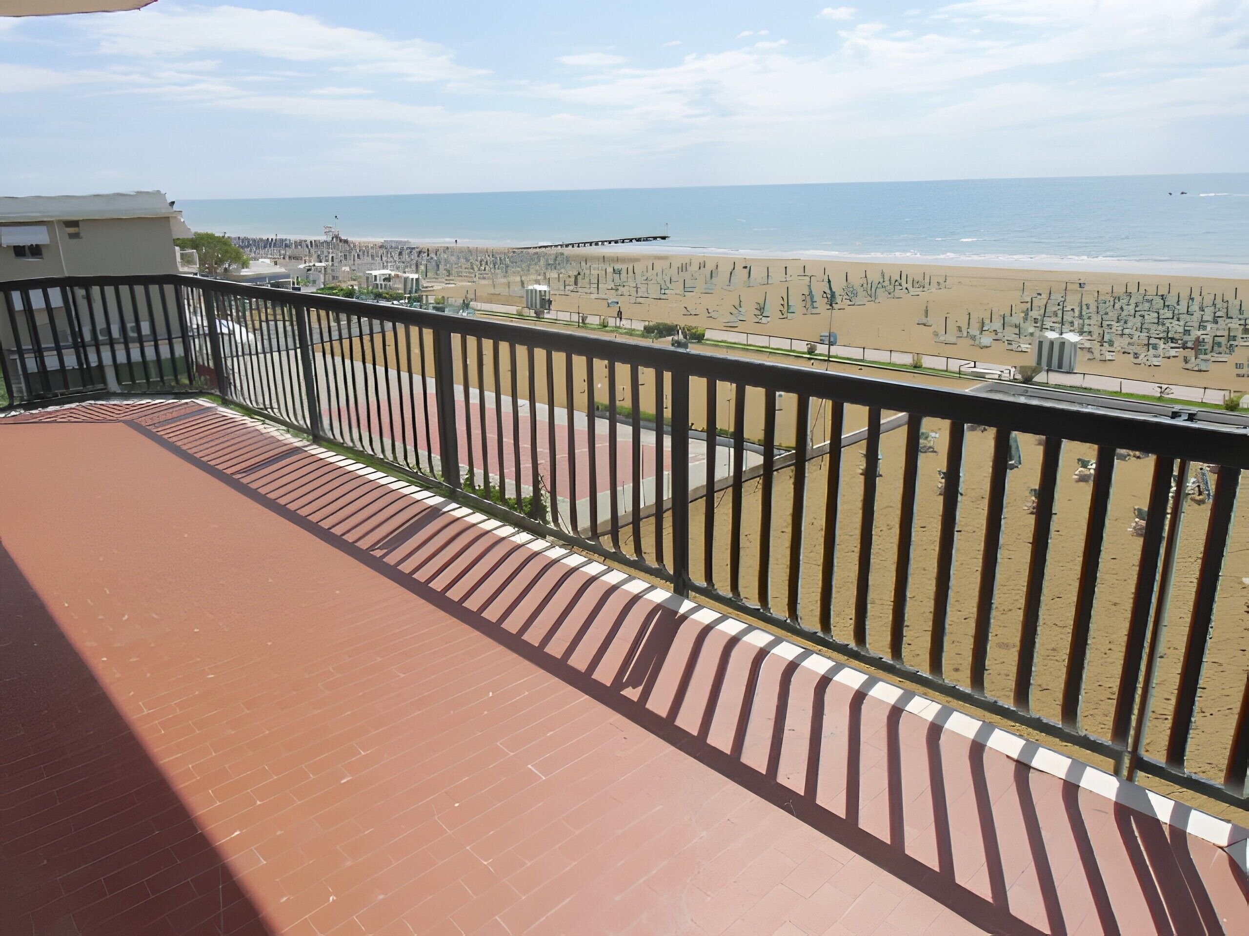 Een balkon met uitzicht op een strand en een steiger.