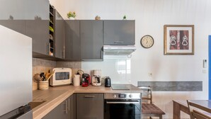 A modern kitchen with stainless steel appliances, a built-in oven, and a coffee maker. - Apartment 'Appartement Des Cedres' with Shared Pool, Wi-Fi and Air Conditioning (Uzès)