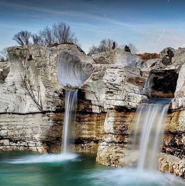 Een waterval stort neer over rotsachtig terrein met helder water.
