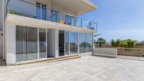 Un edifici modern amb façana de vidre, un balcó i una zona de pati pavimentada.