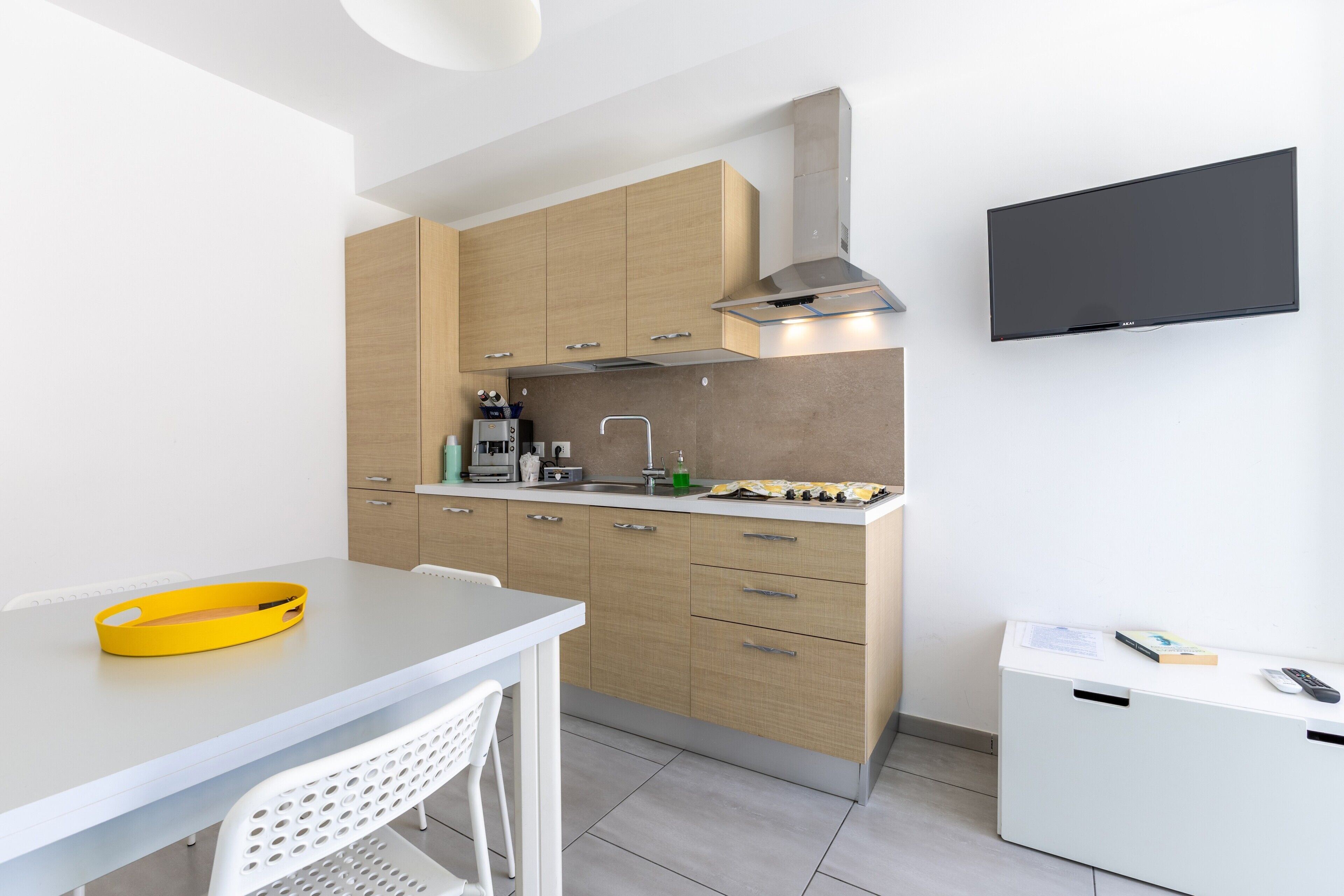 Eine moderne Küche mit Holzausstattung, einem Gasherd, einem eingebauten Backofen und einem flachbildfernseher an der Wand.