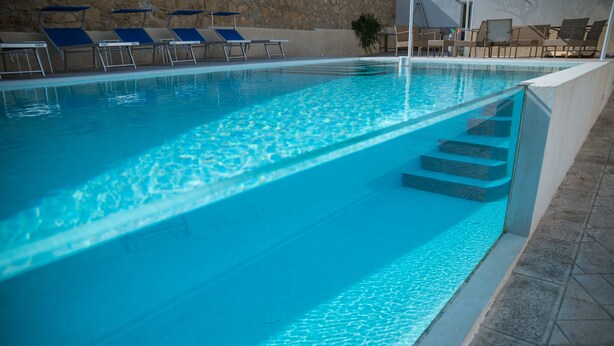 Una piscina amb aigua blava cristal·lina, escales que hi condueixen i gandules al voltant de la vora.