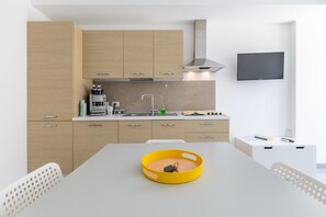 Une cuisine moderne avec des meubles en bois, une cuisinière encastrée et un téléviseur à écran plat fixé au mur.