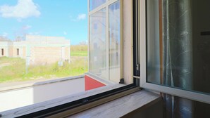 A window with a view of a building and a grassy area. - Surya's House Otranto (Otranto)