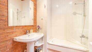 Ein Badezimmer mit Waschbecken, Spiegel, Dusche und einer Holzwand.