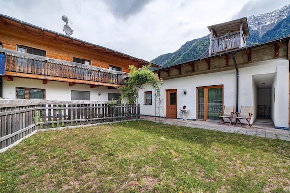 A chalet with a wooden balcony, a small garden, and a mountain view.